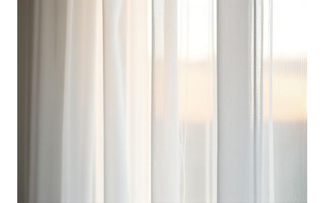 Nærbilde av plissegardiner i et lyst rom, som filtrerer morgenlyset mykt.