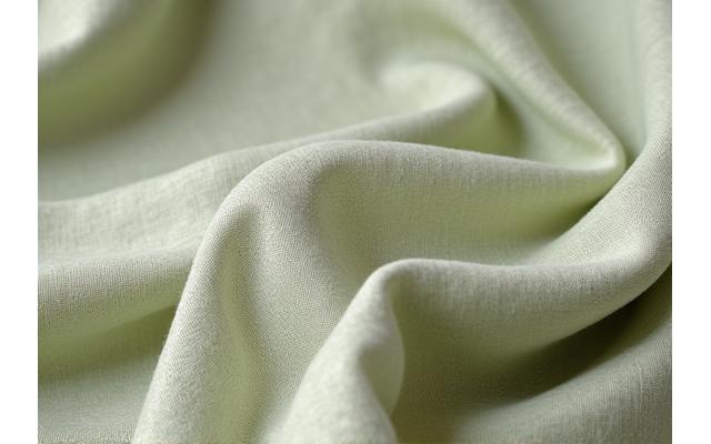 Nærbilde av et tekstilstykke med et miljøsertifiseringsmerke, grønne og duse farger.